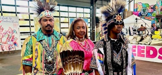 Vaughnda Hilton, her son Andrew Lyn, and Andrew’s son Jordan Lyn stand together—three generations of dancers. Hilton wears a jingle dress adorned with handmade beadwork and rows of metal (healing) cones–each cone represents a day of the year– while her son and grandson wear Grass Dance regalia featuring vibrant colors, intricate ribbonry and fringe, roach (headdress) and decorative elements that highlight traditional artistry.