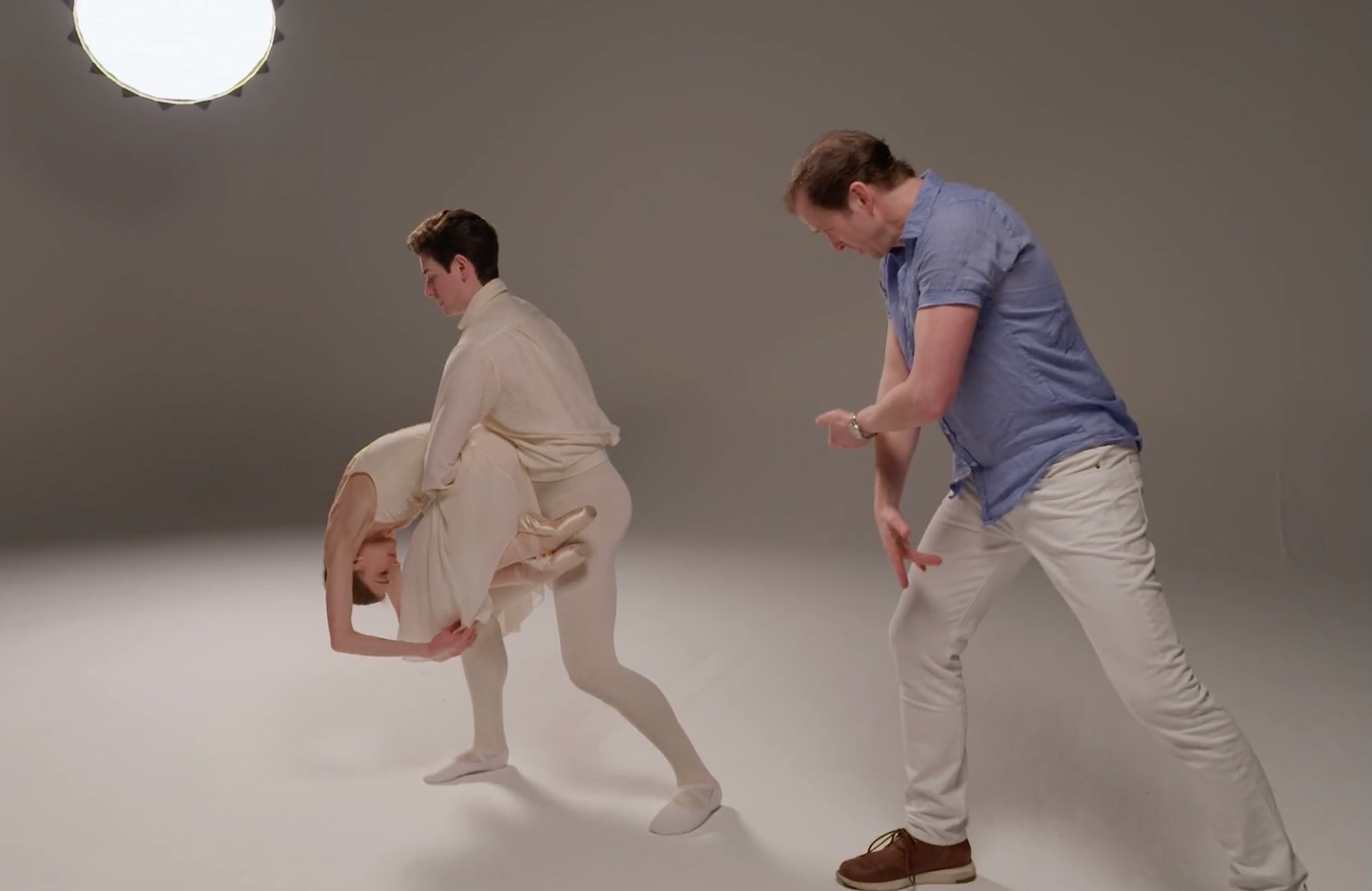 Choreographer Charles Askegard guides a poignant moment as Oksana Maslova collapses into Sterling Baca’s arms. Her knees are drawn to her chest, toes pointed, arms extended overhead, lifted off the floor, expressing grief while supported by her partner.
