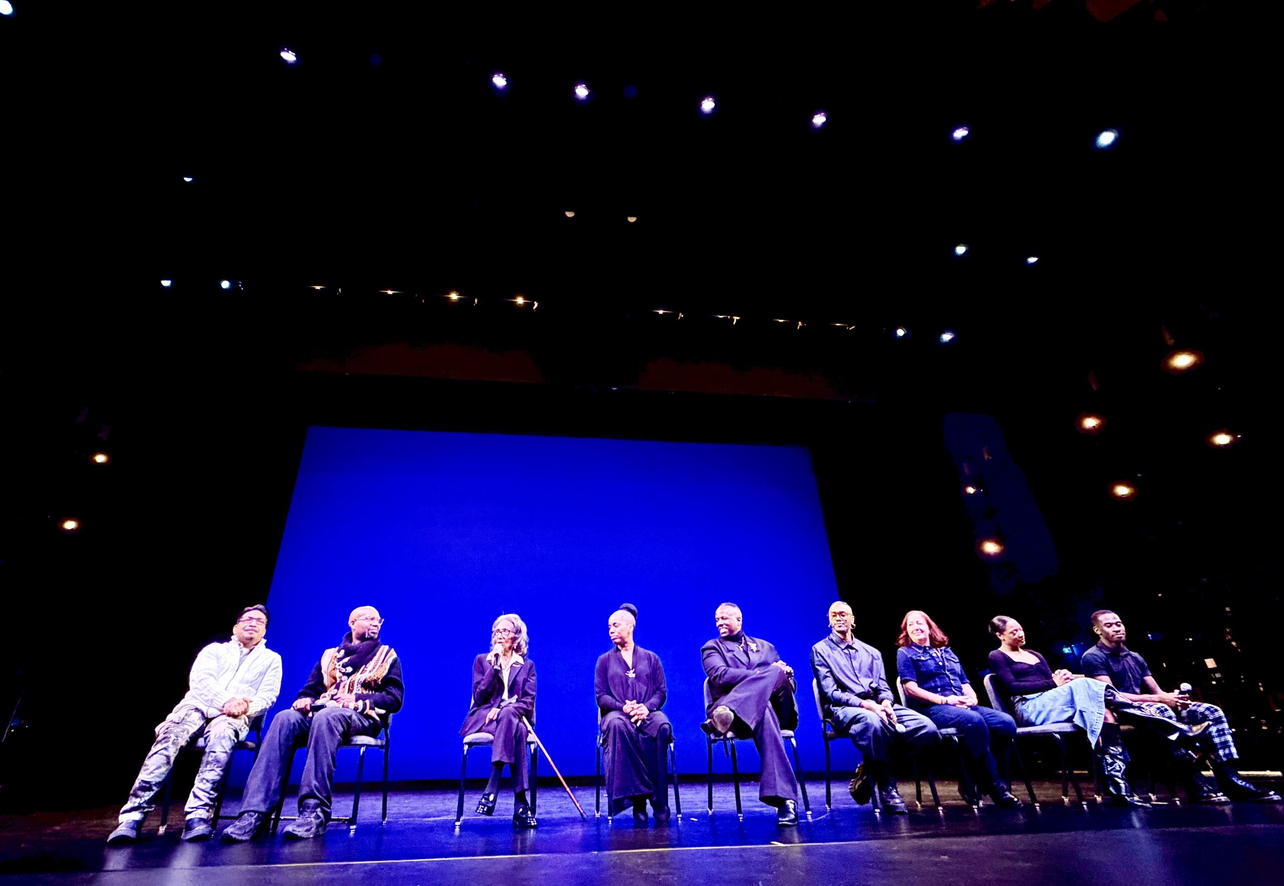 Joan Myers Brown and eight fellow choreographers, dancers, and company leaders seated on a panel discussion on a blue-lit stage at the Perelman Theater, following the performance.
