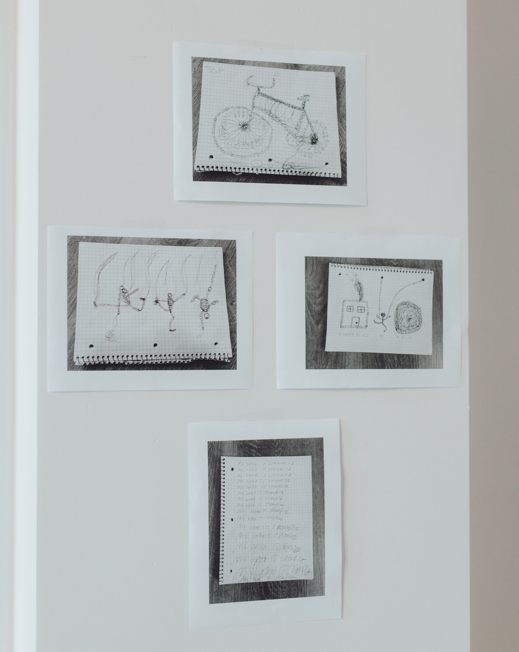 Four photographs of sketches are assembled in a diamond formation on a white table. From top to bottom, the photographs depict: a bicycle made of shoelaces; abstract dancing bodies flinging long shoelace-like objects into the air; a building, dancer, and dark portal; a poem, with words filling the entire page.