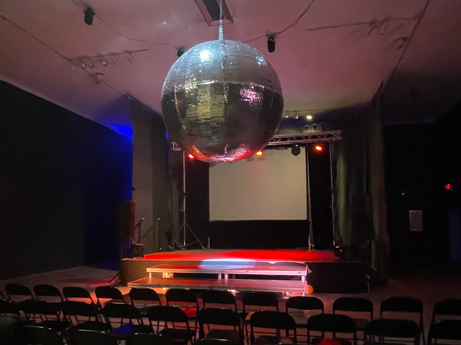 A giant discoball hangs at the back of the theater, Philadelphia’s “biggest”. The stage is awash in red with a spotlight at the lip of the stage. The theater is empty; there is a sense of anticipation as the discoball takes over the frame of the photo.