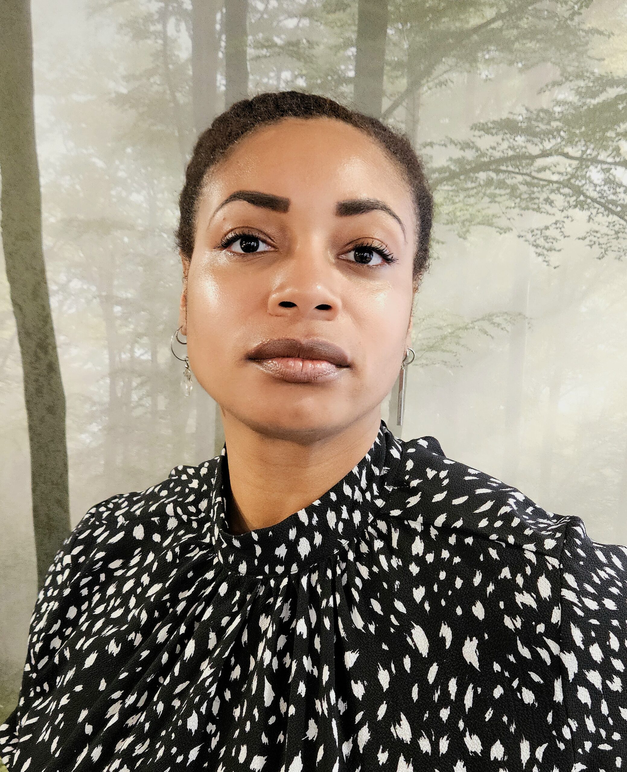 thINKingDANCE writer Noel Price-Bracey looks towards the camera, in front of a background of trees.