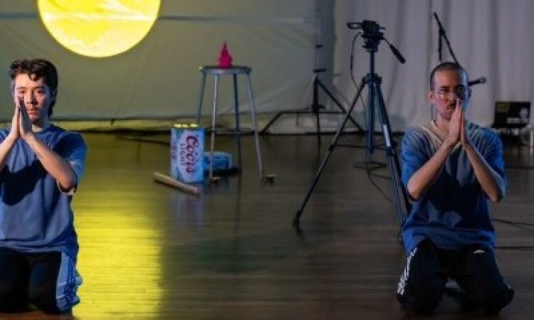 evan ray suzuki and Glenn Potter-Takata kneeling with their hands together in gassho with a projection of the moon in the background.