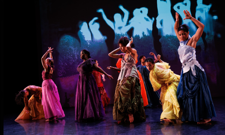 Dancers scattered in a loose line, bend, raise their hands, reach, fold, and step. behind them there is a projected silhouette of this line - a live video feed.