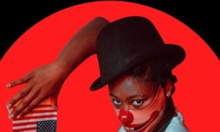 There is a black grassy horizon line and a mostly full red moon rising. In the circle of the moon is a young black woman in a short sleeve white shirt and a black vest. Her Right arm is raised so her hands can frame above and below a small upside down american flag. She wears a circus style top hat and a mask over the bottom half of her face that is a clown's wide smile.