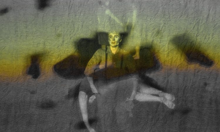 A projection screen shows big black chunks of falling debris. Behind that, we see a person with dirt on their cheeks and wearing dark overalls, carrying another person in feont of them across their stomach. The person being carried wears a gray dress, and their bare limbs hang lifeless. Beyond these two, in the distance, we can faintly see another pair, facing one another with their hands extended towards one another.